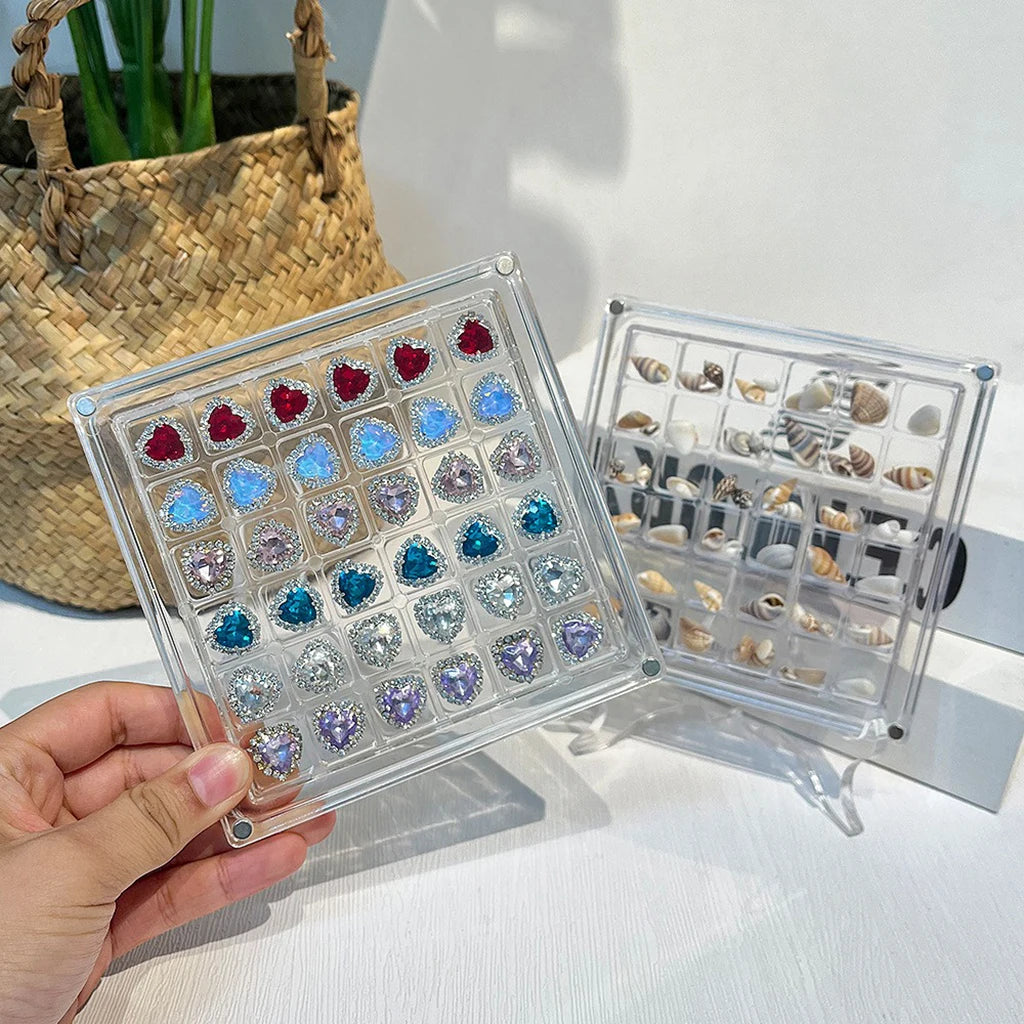 A clear acrylic magnetic display box filled with various colored and shaped seashells.