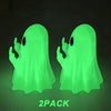 A pair of glowing neon green ghost figurines with playful arms displayed against a dark background.
