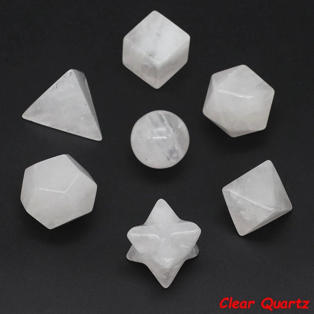 A collection of seven clear quartz crystals in various geometric shapes and angles displayed on a dark surface.