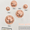 A collection of rose gold disco balls of various sizes mounted on a white background.