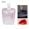 Clear glass dropper bottle of nourishing fruit lip oil gloss with a drop of oil on the surface and a swatch of red lip oil.
