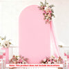 A pink arched backdrop with floral greenery and sheer pink fabric draping, designed for wedding photography.
