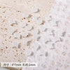 A collection of small, translucent white cat head glass beads for jewelry making are scattered on a white, fluffy surface.