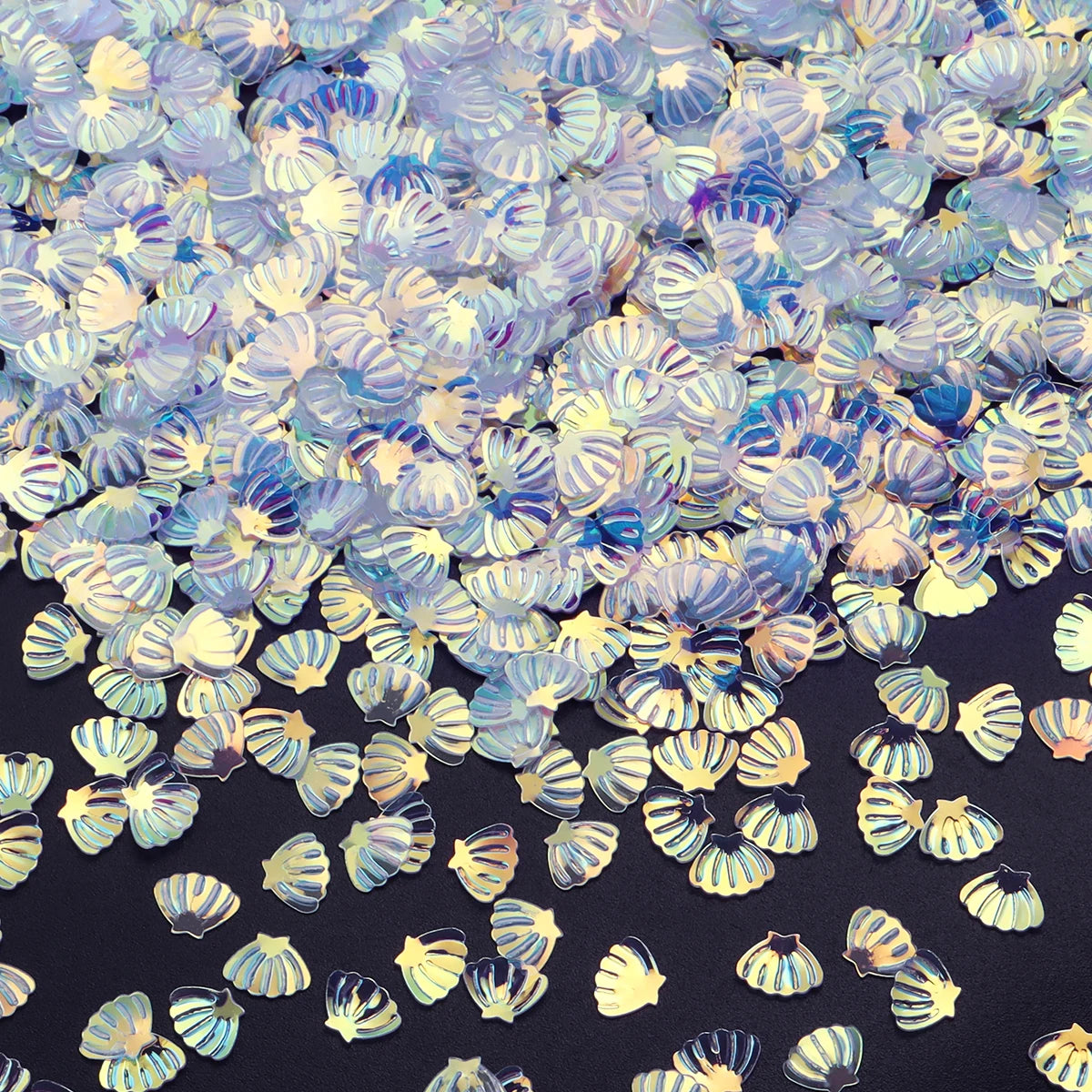 A close-up of iridescent blue and gold sea shell PVC sequins scattered on a dark surface.