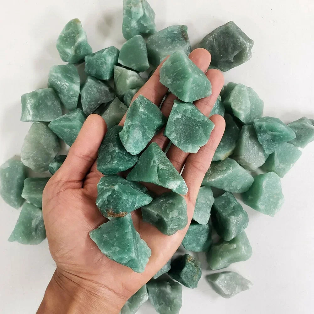 A hand holds a cluster of light green natural raw healing crystal stones for chakra balancing and home decor.