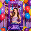 A young woman posing in a purple and gold balloon-decorated photo frame backdrop for a birthday party