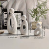 A white modern resin family statue featuring three figures standing on a light surface.