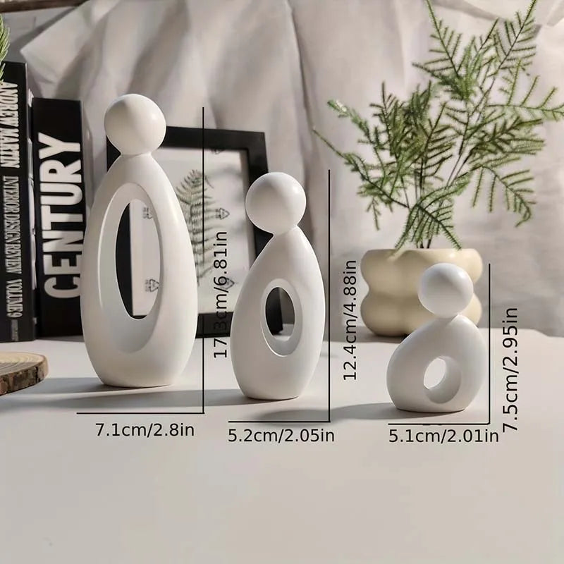 A white modern resin family statue featuring three figures standing on a light surface.