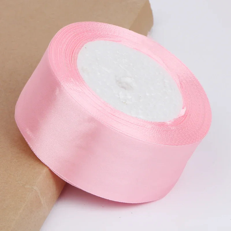 Roll of pink satin ribbon used for crafts, gift wrapping, or DIY projects