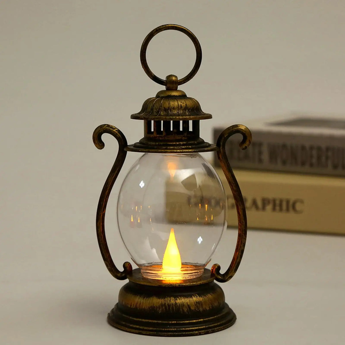 A vintage brass battery-powered desk lamp with an amber glow inside a clear glass bulb.