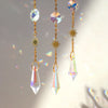 A delicate gold chain holds a moon-shaped crystal pendant with a rainbow prism, featuring sunburst accents.