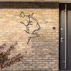 A modern silhouette of a cat and woman's profile carved into a textured brick wall.