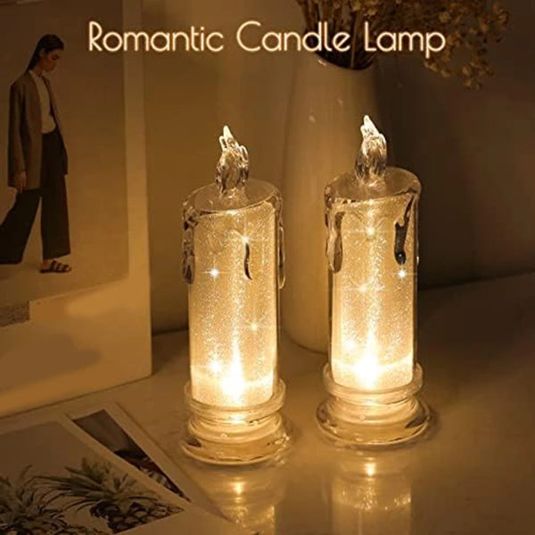 A set of four clear glass pillar candles glowing with warm light on a surface.