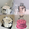 A display of three elegant ribbon bow cakes in white, pink, and bright pink with black accents.
