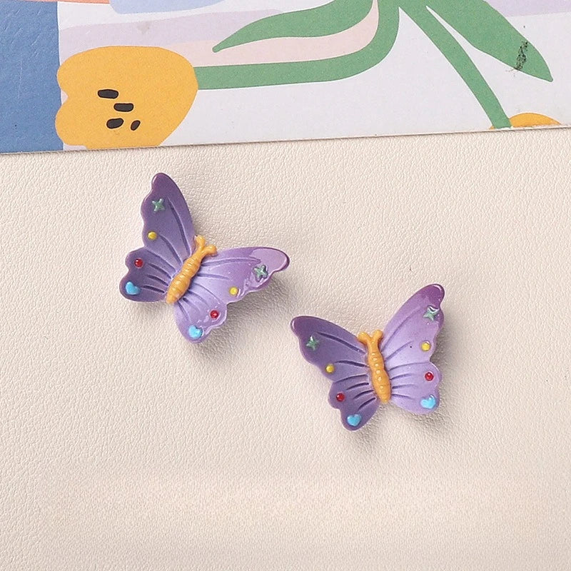 Purple resin butterfly and bee fridge magnets against a light background.