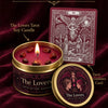 A candle in a gold tin labeled The Lovers Tarot Guidance Card with red wax and decorative elements.