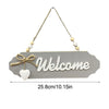 A wooden welcome sign with the word Welcome carved into it, suspended by twine and small beads.