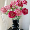 A bouquet of pink and magenta silk peony flowers arranged in a black vase.