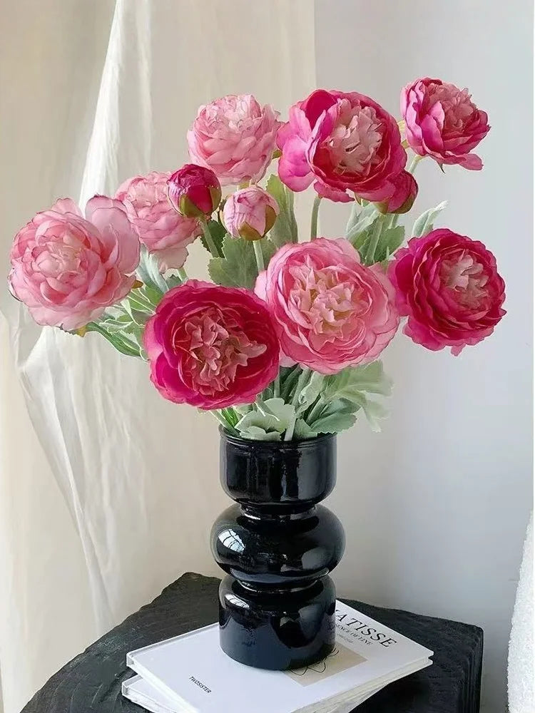 A bouquet of pink and magenta silk peony flowers arranged in a black vase.