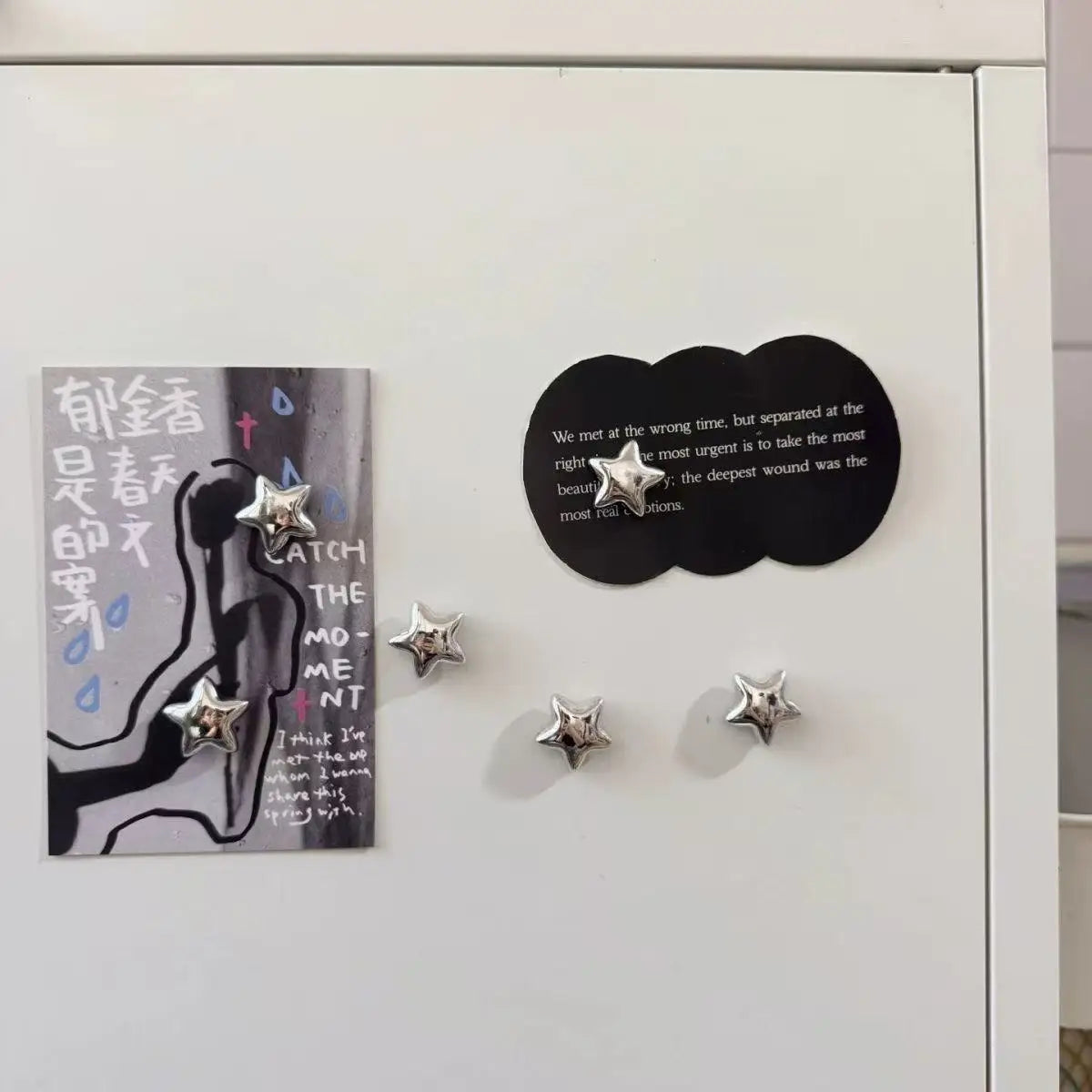 A set of decorative heart and star fridge magnets featuring a black sign with text and several silver star-shaped magnets.