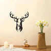 A black metal deer head wall sculpture is displayed next to a vase of white flowers on a wooden surface.