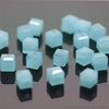 A collection of light blue square cut glass crystal beads for jewelry making displayed on a reflective surface.
