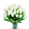 A bouquet of white artificial tulips in a clear glass vase.
