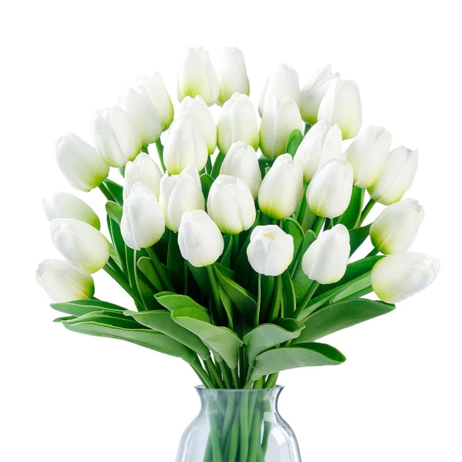 A bouquet of white artificial tulips in a clear glass vase.