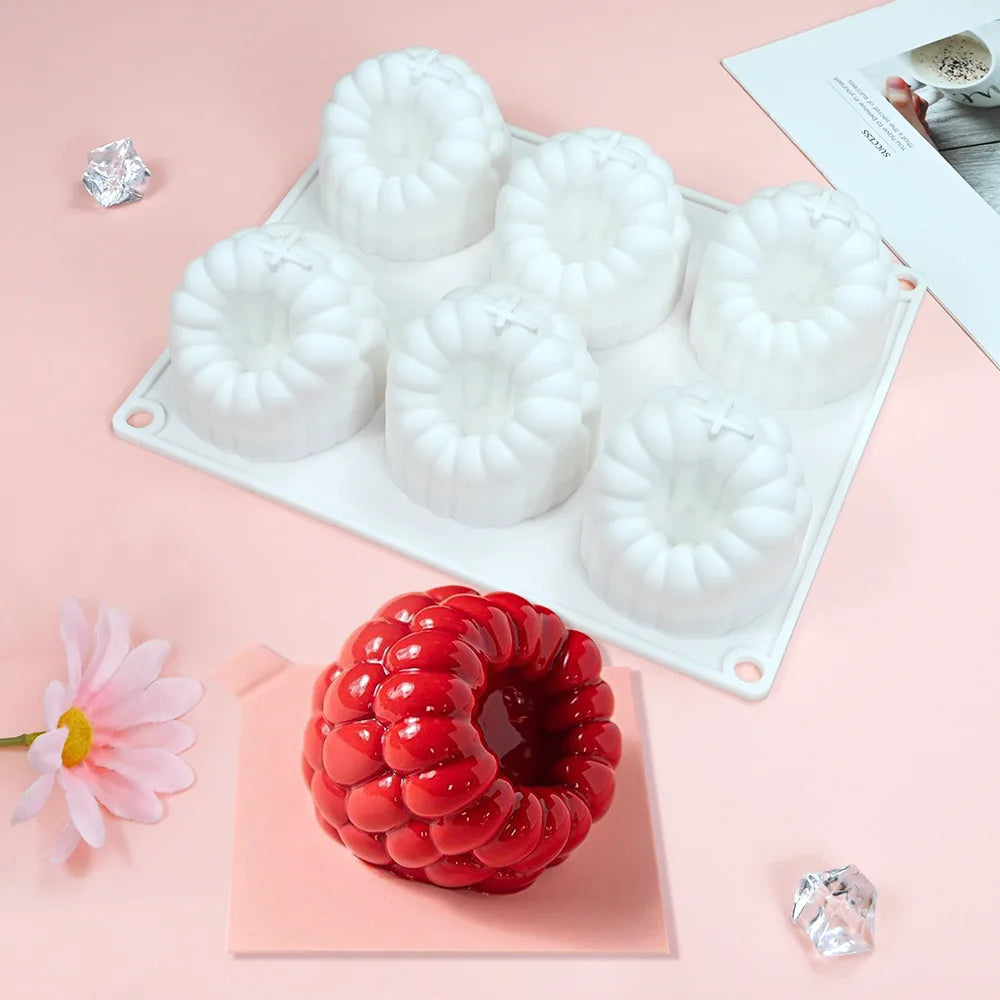 White silicone raspberry mousse molds arranged on a white tray with decorative sugar crystals nearby.