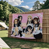 A large pink anime flag tapestry featuring characters from K-On! in a forest outdoor setting.