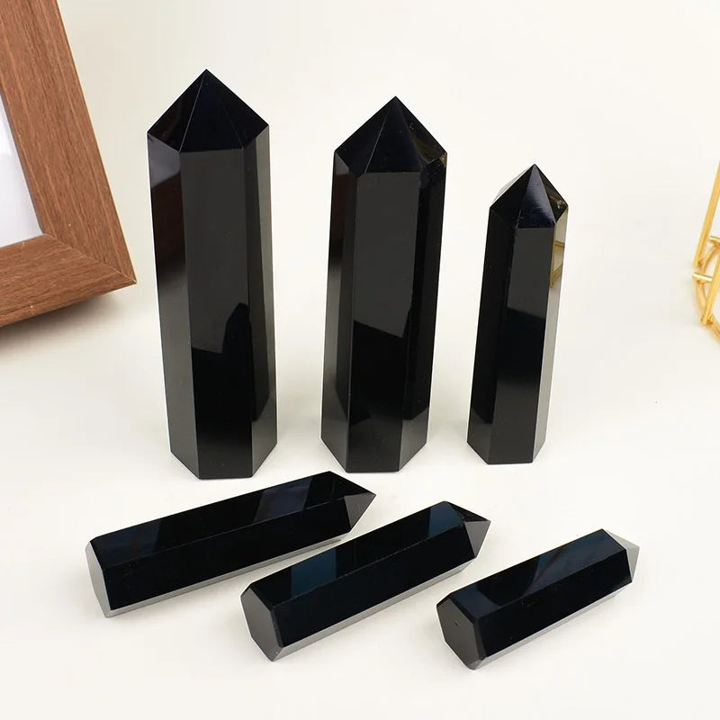 A collection of black obsidian crystal obelisks and rectangular points displayed on a white background.