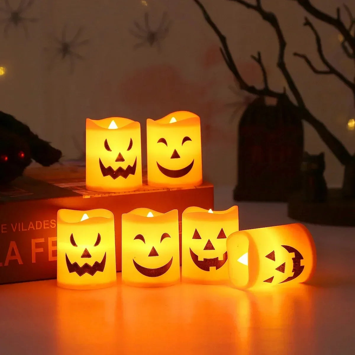 A row of glowing orange LED candles shaped like smiling jack-o'-lanterns and skulls on a white surface.