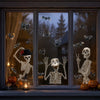A window display featuring Halloween skull and bat static cling stickers against a dark background.