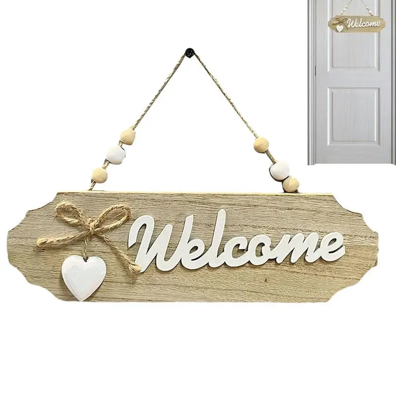 A wooden welcome sign with the word Welcome carved into it and adorned with small white and beige beads, hanging from a rope.