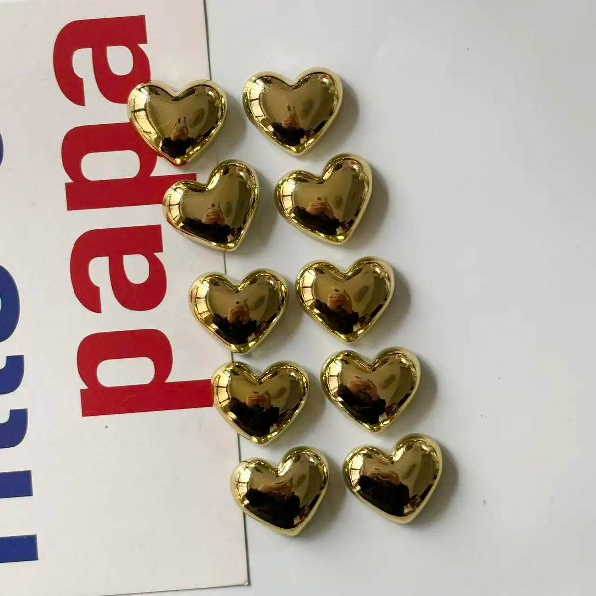 A set of eleven gold heart-shaped fridge magnets arranged in a row.