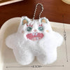 A white fuzzy plush monster with pink accents and a silver chain attached, resting on a white plate.