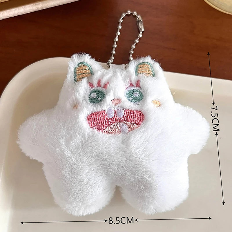 A white fuzzy plush monster with pink accents and a silver chain attached, resting on a white plate.