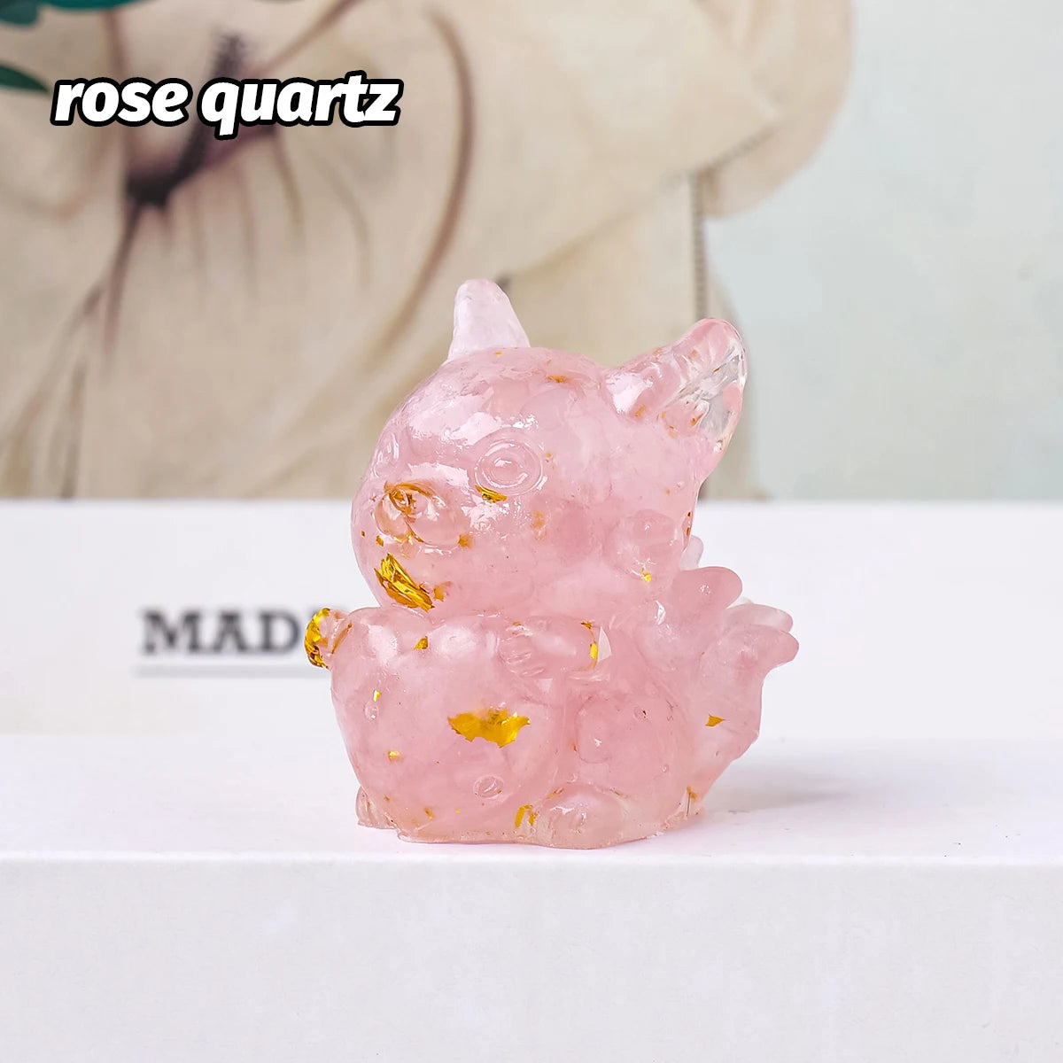 A small, translucent pink rose quartz sculpture shaped like a rabbit, decorated with gold flakes.