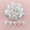 A pile of small, clear acrylic cross shape beads for DIY jewelry making