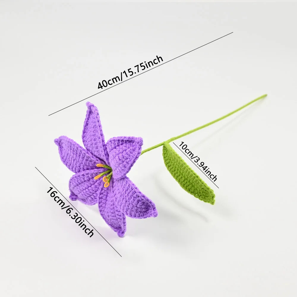 Hand-crocheted purple lily flower with a green stem and leaf, displayed against a white background.