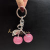 Silver keychain featuring a pink glitter cherry charm on a black background.
