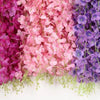 A close-up of artificial wisteria flower garlands in shades of pink, purple, and magenta.