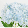 A cluster of light blue artificial hydrangea flowers on a green leaf.
