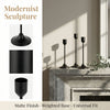 A set of matte black modernist metal taper candle holders displayed on a stone mantelpiece.