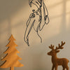 A black line art silhouette of a woman's profile on a wall, next to a wooden deer figurine.