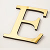 A gold acrylic mirror letter E wall sticker for decorative purposes.