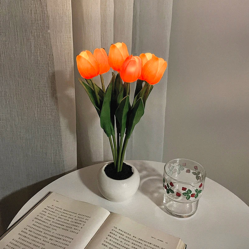 A bouquet of bright orange LED tulips in a white ceramic pot, displayed against a light background.