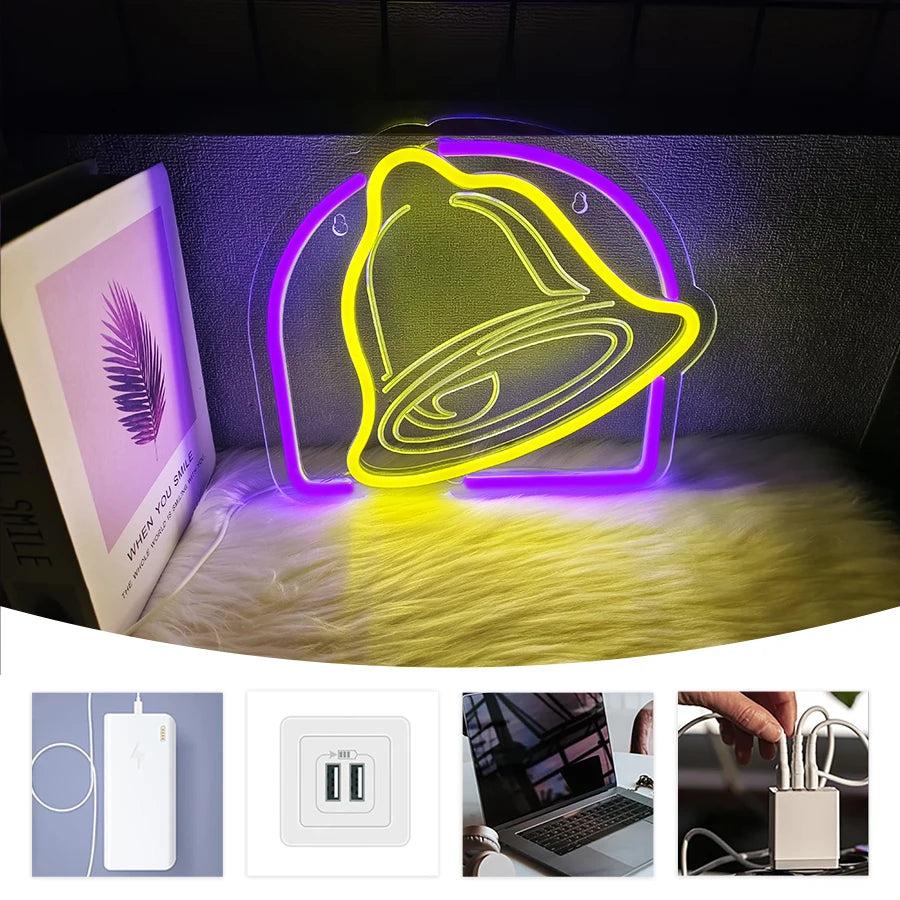 A yellow neon effect bell sign illuminated in purple light, shown next to a white LED and laptop.