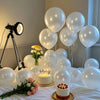 A display of pearl white latex balloons, including a cake and floral arrangement, set on a white cloth.
