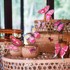 A decorative set of twelve pink and multicolored 3D butterfly wall stickers displayed in a woven basket.